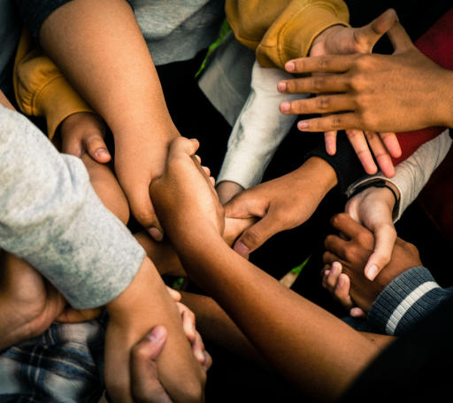 A close-up of a bunch of diverse people clasping hands together